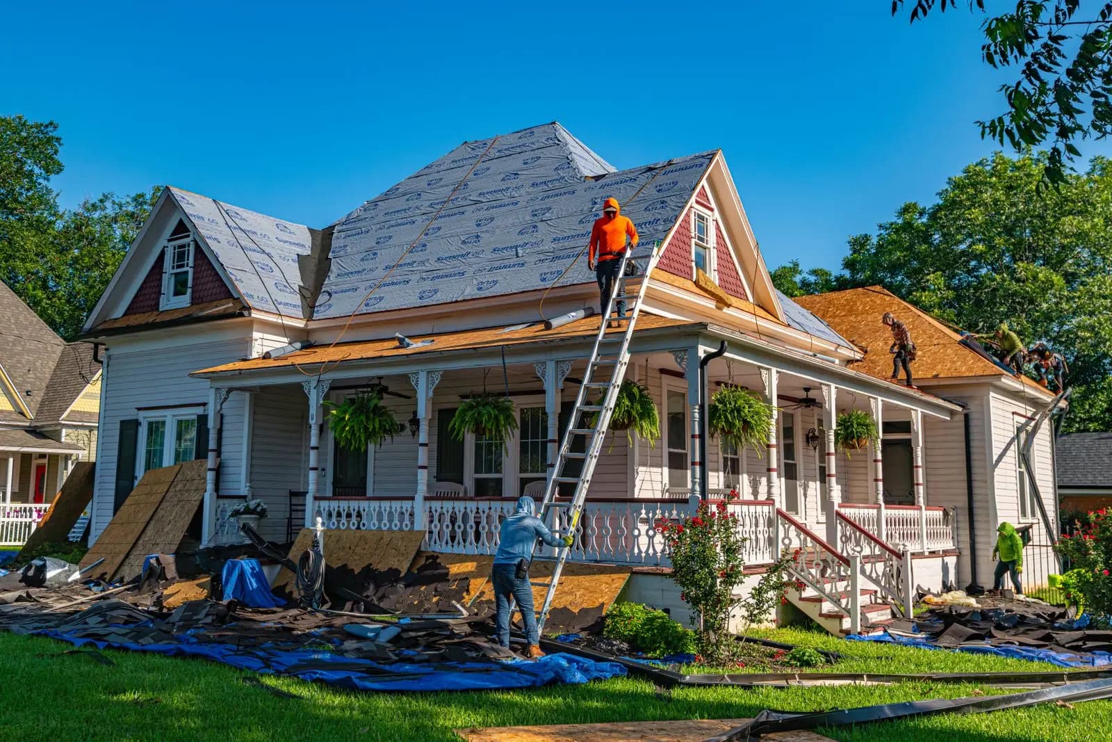 Crew replacing the roof on a two-story Victorian house